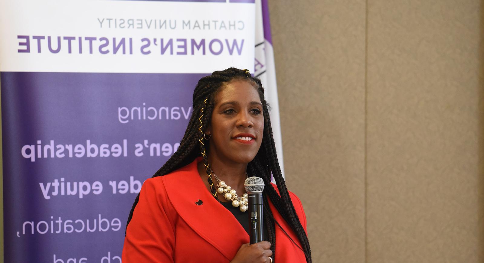 Photo of a woman presenting in front of a banner that reads Chatham University's Women's Institute