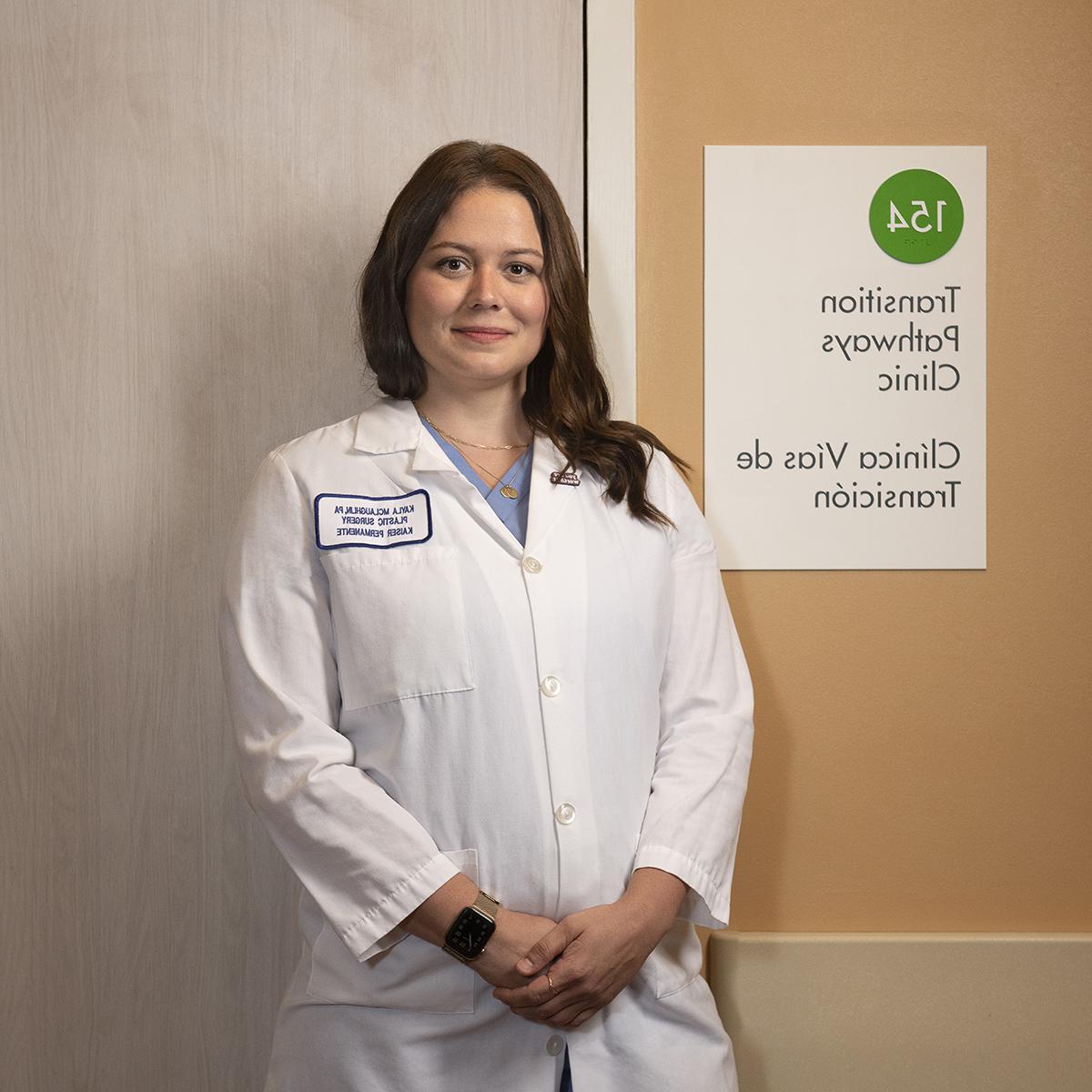 Photo of Kayla McLaughlin in a white doctors coat, standing in a hospital hallway